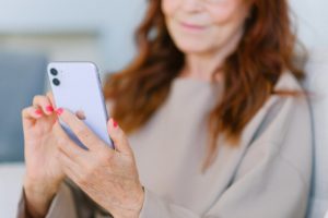 An older woman with red hair using her smartphone while smiling