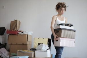 Woman holding boxes next to a pile of clutter in her Shoreline home
