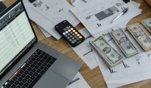 A laptop, a calculator, and some banknotes on a table